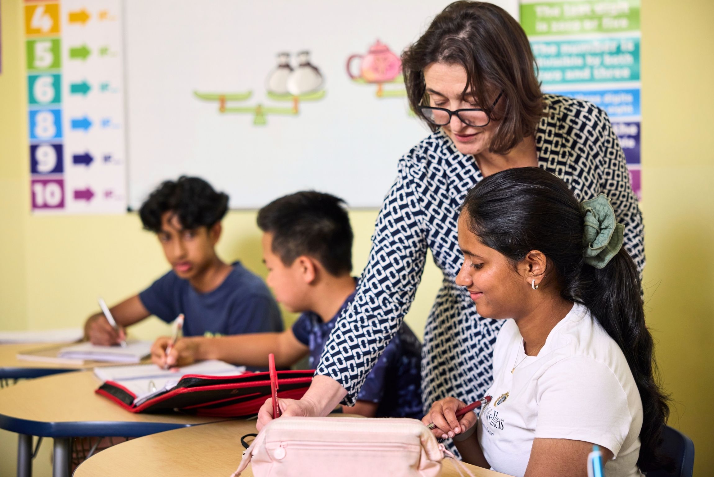 teacher helping student at desk