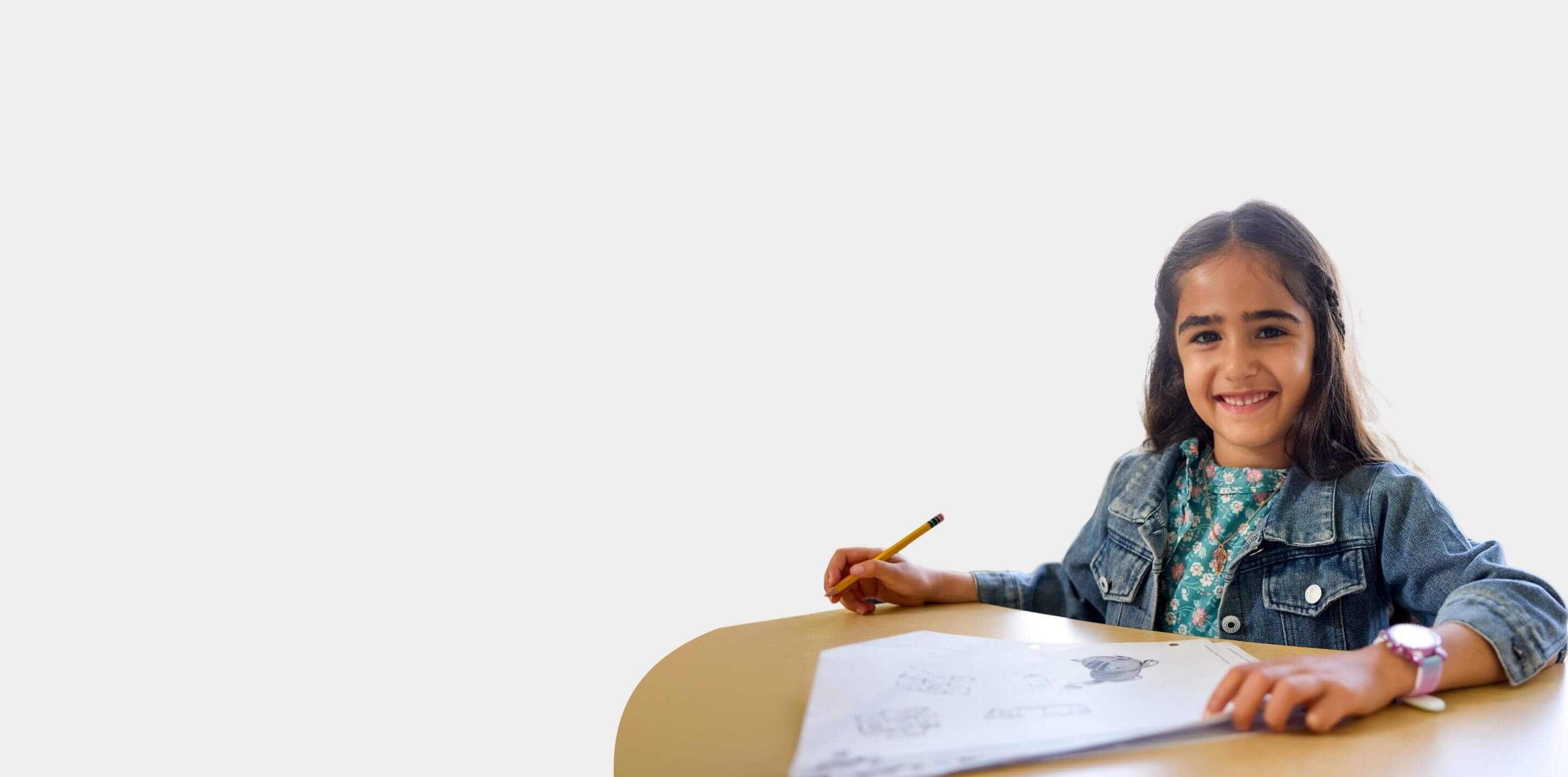 A Dubai student smiling at the camera working on her math homework