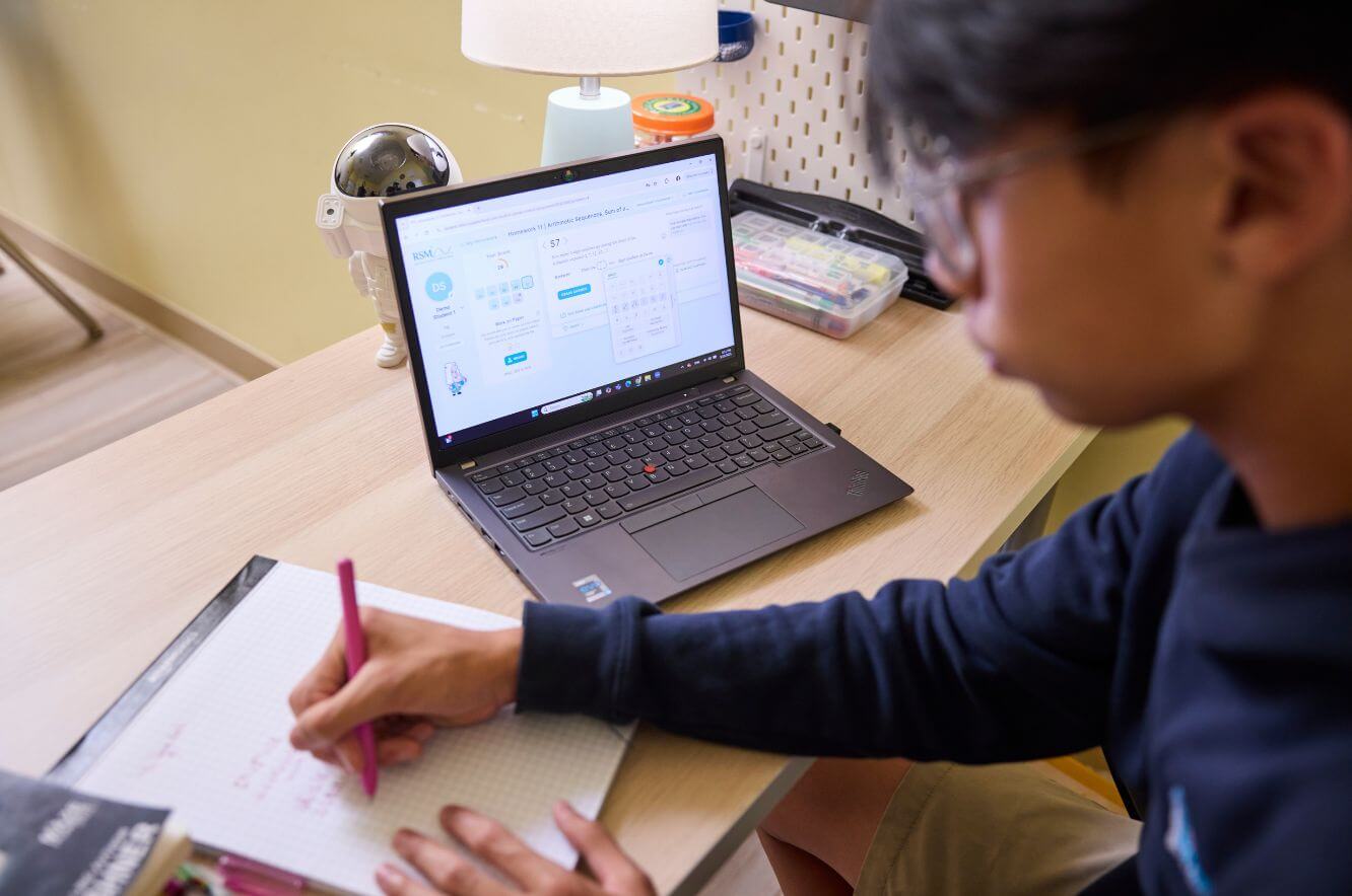 boy working on math classwork in front of laptop